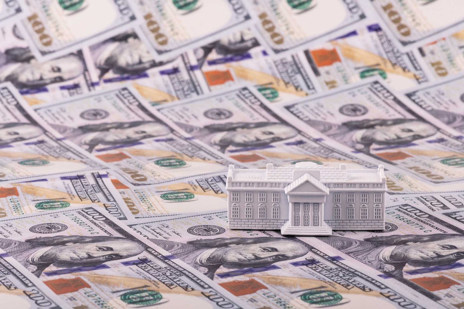 Model house resting on U.S. hundred-dollar bills